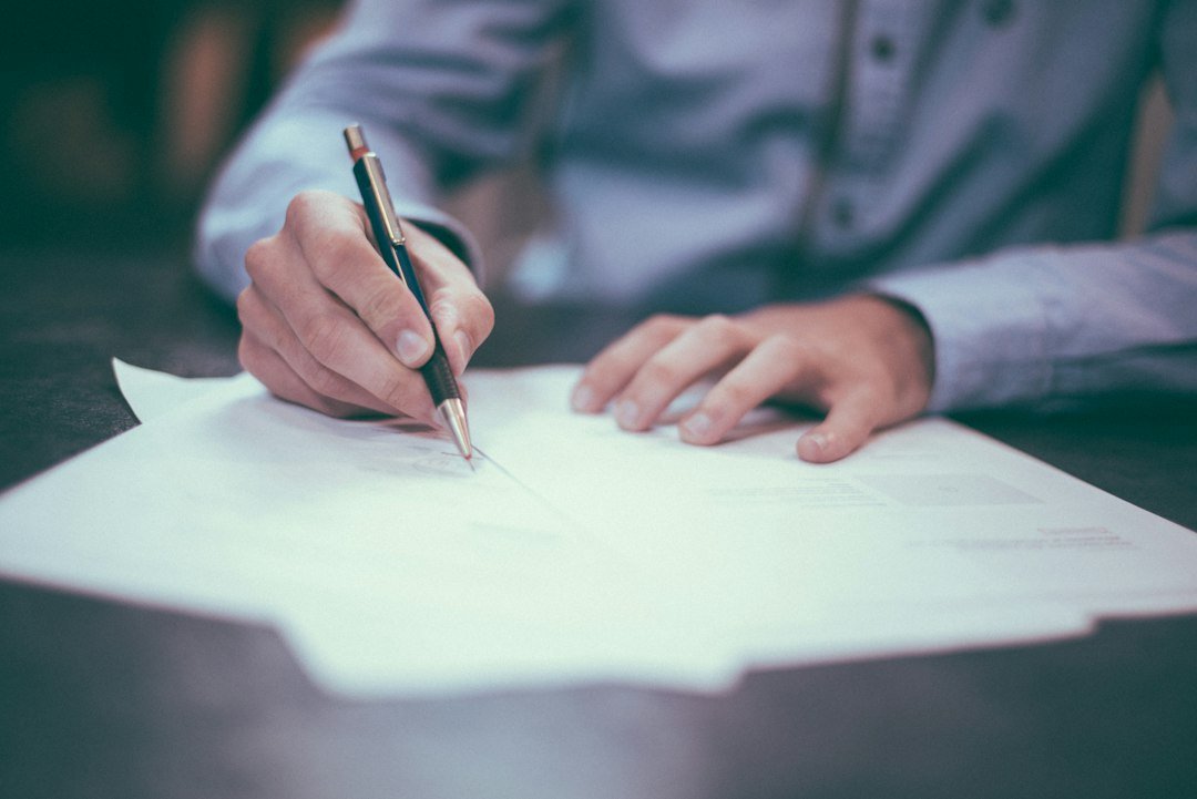 Person writing notes on paper representing legal terms and a website disclaimer